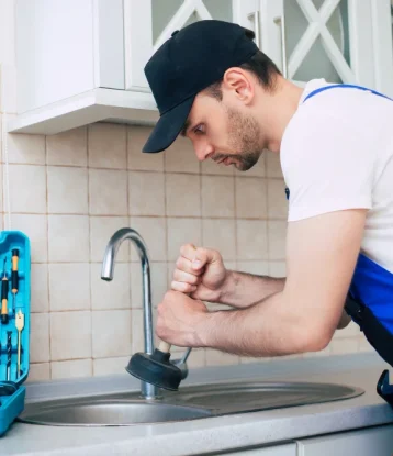 handyman uniform is cleaning clogged kitchen sink with help plunger