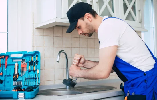 handyman uniform is cleaning clogged kitchen sink with help plunger