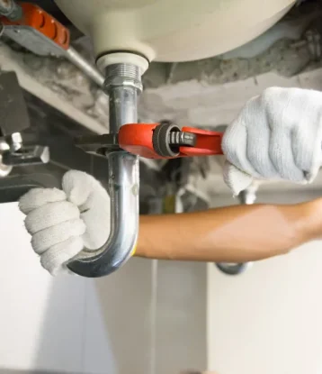 plumber fixing white sink pipe with adjustable wrench