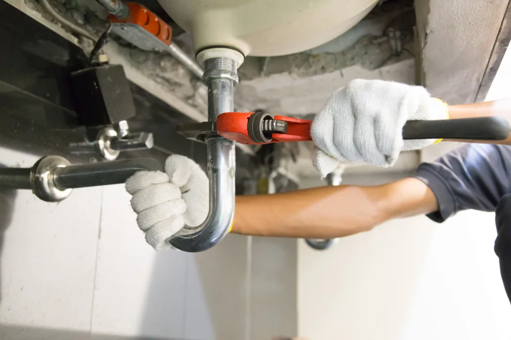 plumber fixing white sink pipe with adjustable wrench